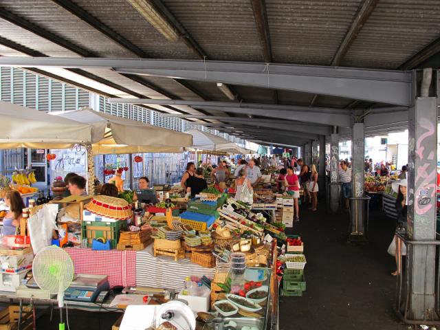 Banchi di frutta e verdura sotto la tettoia di un mercato coperto