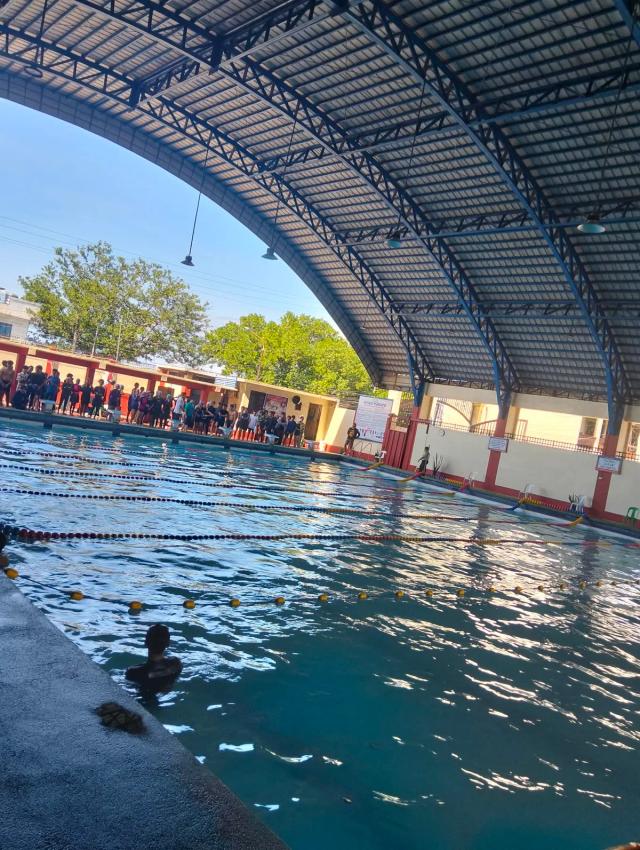 Una piscina coperta a corsie con un gruppo di persone a bordo vasca durante una lezione