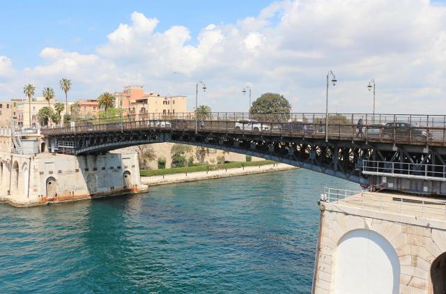 Il Ponte Girevole di Taranto sul canale navigabile, con le case della città sullo sfondo e l'acqua azzurra