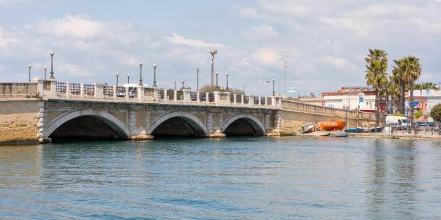Il Ponte di Pietra di Taranto, a tre arcate, visto dall’acqua del Mar Piccolo in una giornata di sole con nuvole